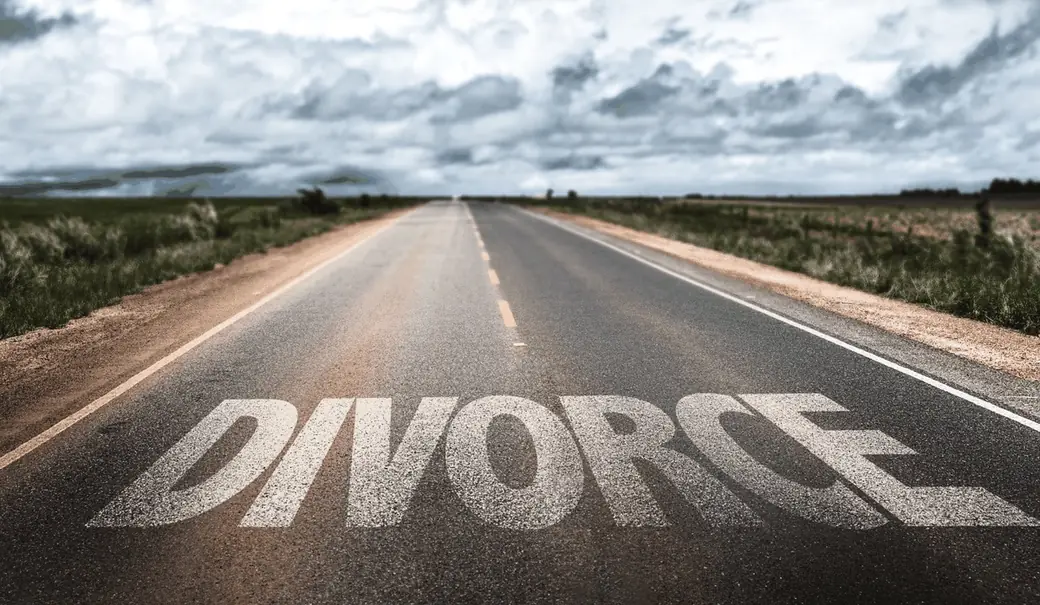 A long open road with the word DIVORCE painted on the asphalt