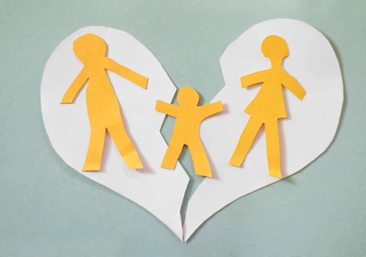 Paper family figures on a torn paper heart