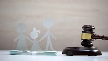 Paper family cutout beside a gavel, representing family law